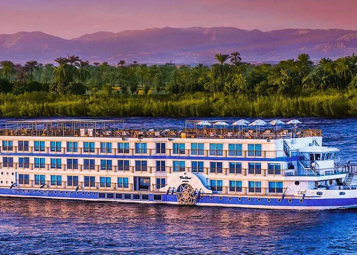 Luxury Oberoi cruise boat on tranquil waters, showcasing elegant design and scenic surroundings.