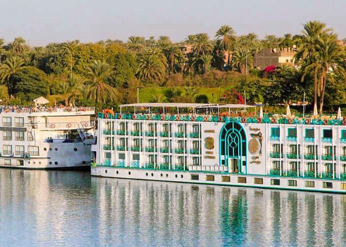 Luxury cruise ship sailing on the Nile River in Egypt, showcasing beautiful landscapes and historic sites.