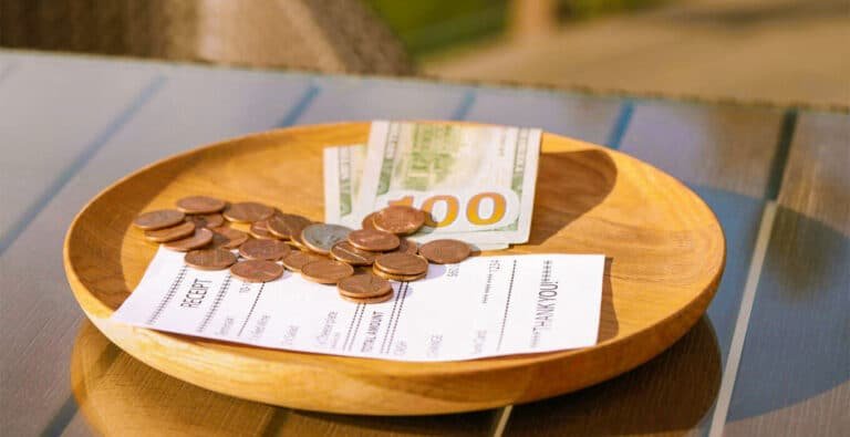 wooden-plate-with-payment-for-order-and-receipt-on-table-closeup Close-up of a wooden plate with payment for an order and a receipt on a table.