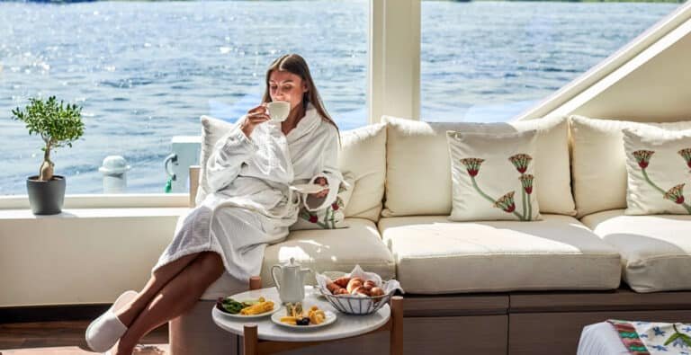 A-stunning-photo-of-a-tourist-inside-one-of-the-cruise-ship’s-cabins. Tourist in a bathrobe enjoys morning tea in a luxurious Nile River cruise cabin.