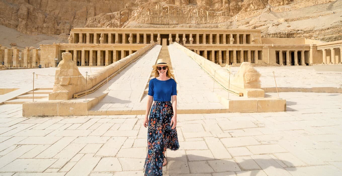 Tourist in a blue dress walks ramp to the Hatshepsut Temple in Luxor, Egypt.