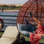 Tourist relaxing in a hanging egg chair swing on the deck of a Nile Cruise ship vacation.