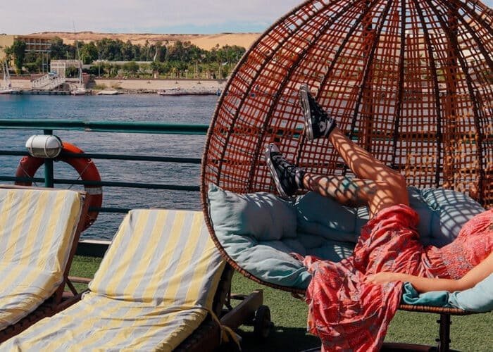 Tourist relaxing in a hanging egg chair swing on the deck of a Nile Cruise ship vacation.