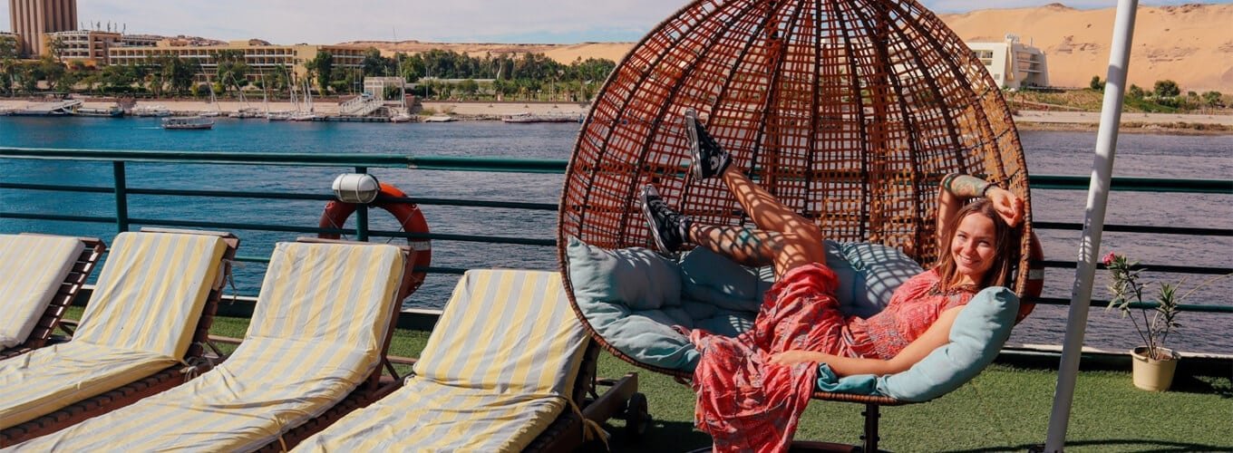 Tourist relaxing in a hanging egg chair swing on the deck of a Nile Cruise ship vacation.