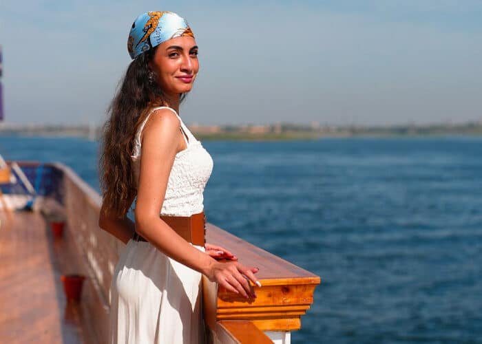 Young woman standing on the deck of a boat with a river and distant shore in the background